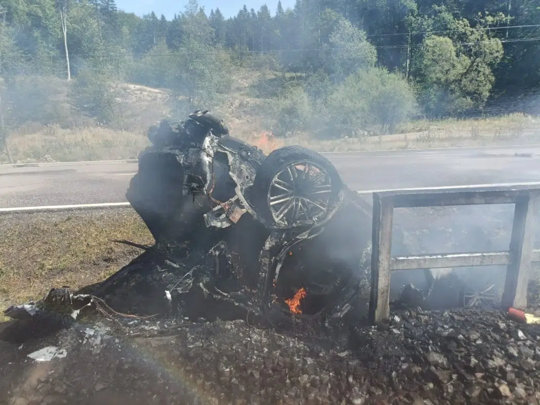 Mașină arsă pe șosea lângă pădure