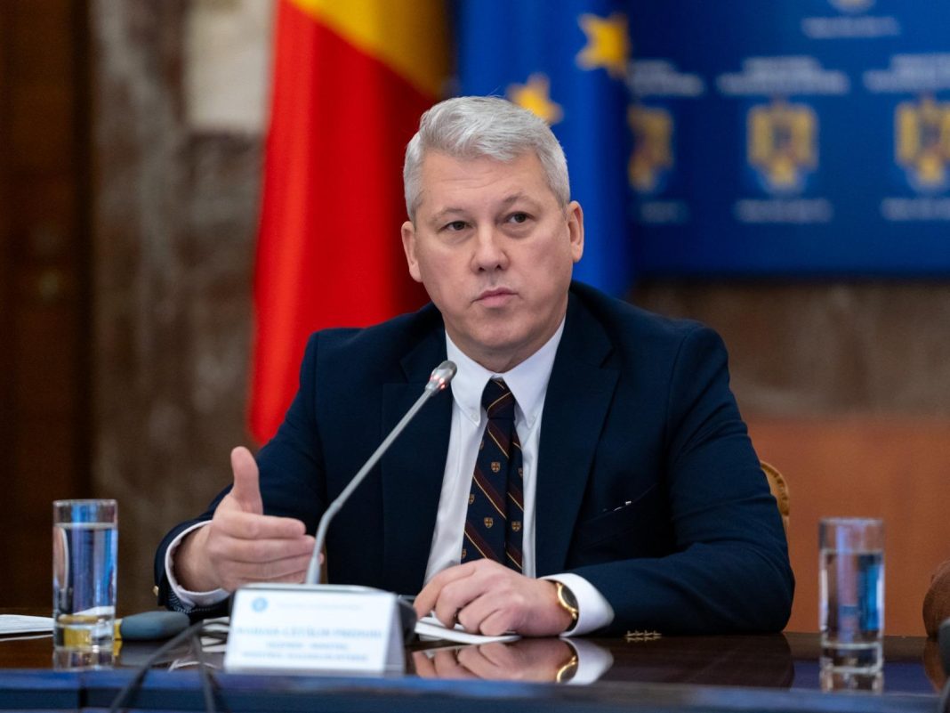 Oficial guvernamental vorbind la conferință, steaguri în fundal