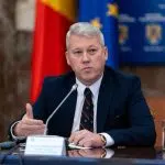 Oficial guvernamental vorbind la conferință, steaguri în fundal