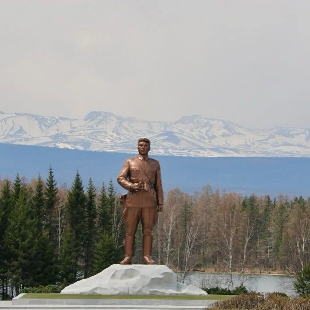 Statuie bronz în fața muntelui împădurit