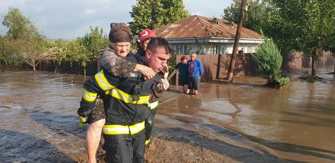 Pompier salvând o bătrână în timpul inundațiilor