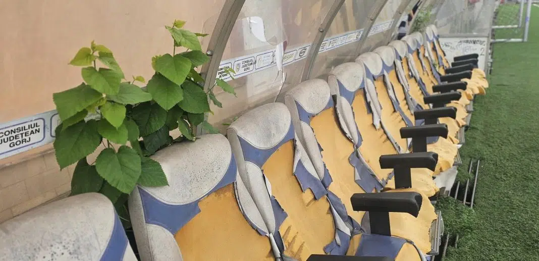 Tribună stadion cu scaune albastre și galbene uzate