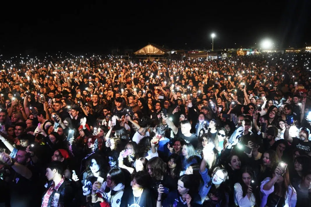 Mulțime la concert noaptea, luminată de telefoane.