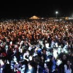 Mulțime la concert noaptea, luminată de telefoane.