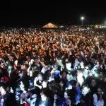 Mulțime la concert noaptea, luminată de telefoane.