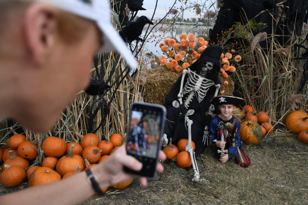 Copil costumat, dovleci și schelet decorativ pentru Halloween.