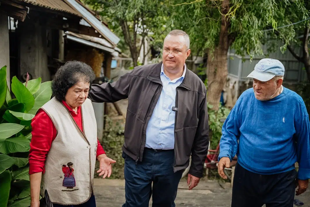 Trei persoane vârstnice conversând într-o curte rurală