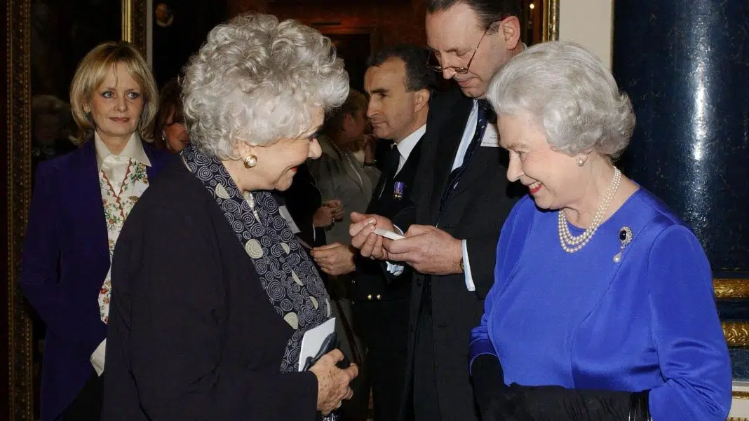 Regina Elisabeta a II-a a Marii Britanii discută cu actrița Dame Joan Plowright la o recepție organizată la Palatul Buckingham pe 11 martie 2004, unde celebrități, scriitori, vedete sportive, academicieni și oameni de afaceri s-au numărat printre numeroasele femei de succes salutate de Familia Regală